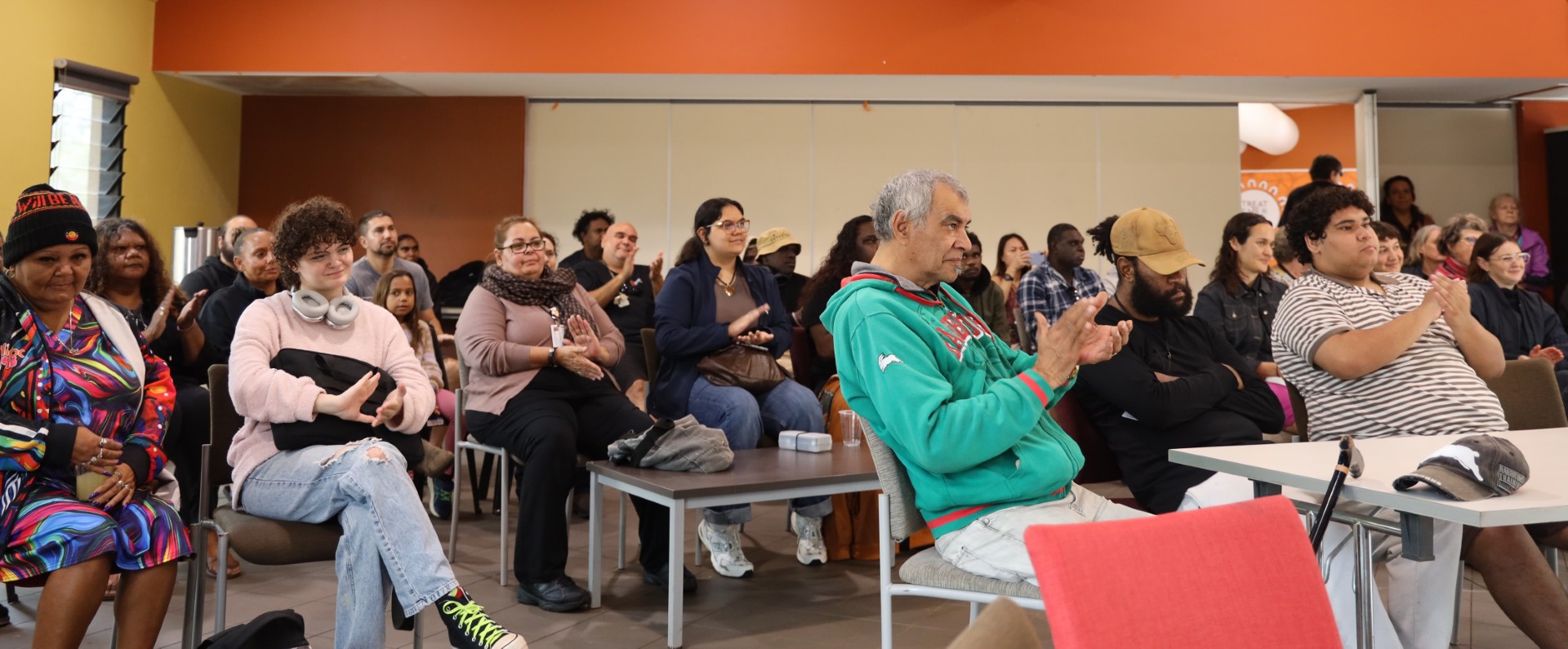 Attendees of the Arne ingkerreke apurtelhe-ileme launch at Batchelor Institute. A large group of people sit applauding the project launch out of shot.