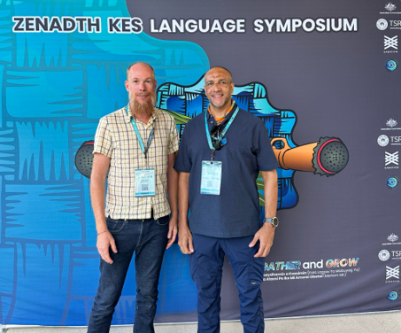 Photo of two men standing in front of a conference banner