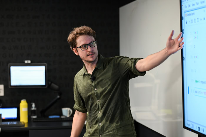 A  photograph of a man gesturing to a smart board